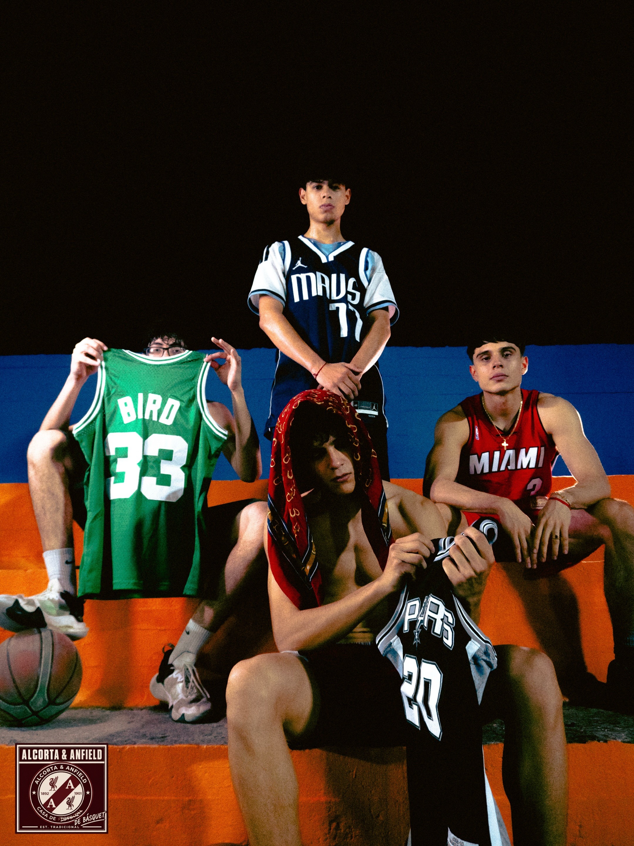 Los cuatro chicos juntos con camisetas de básquet en las gradas de la cancha