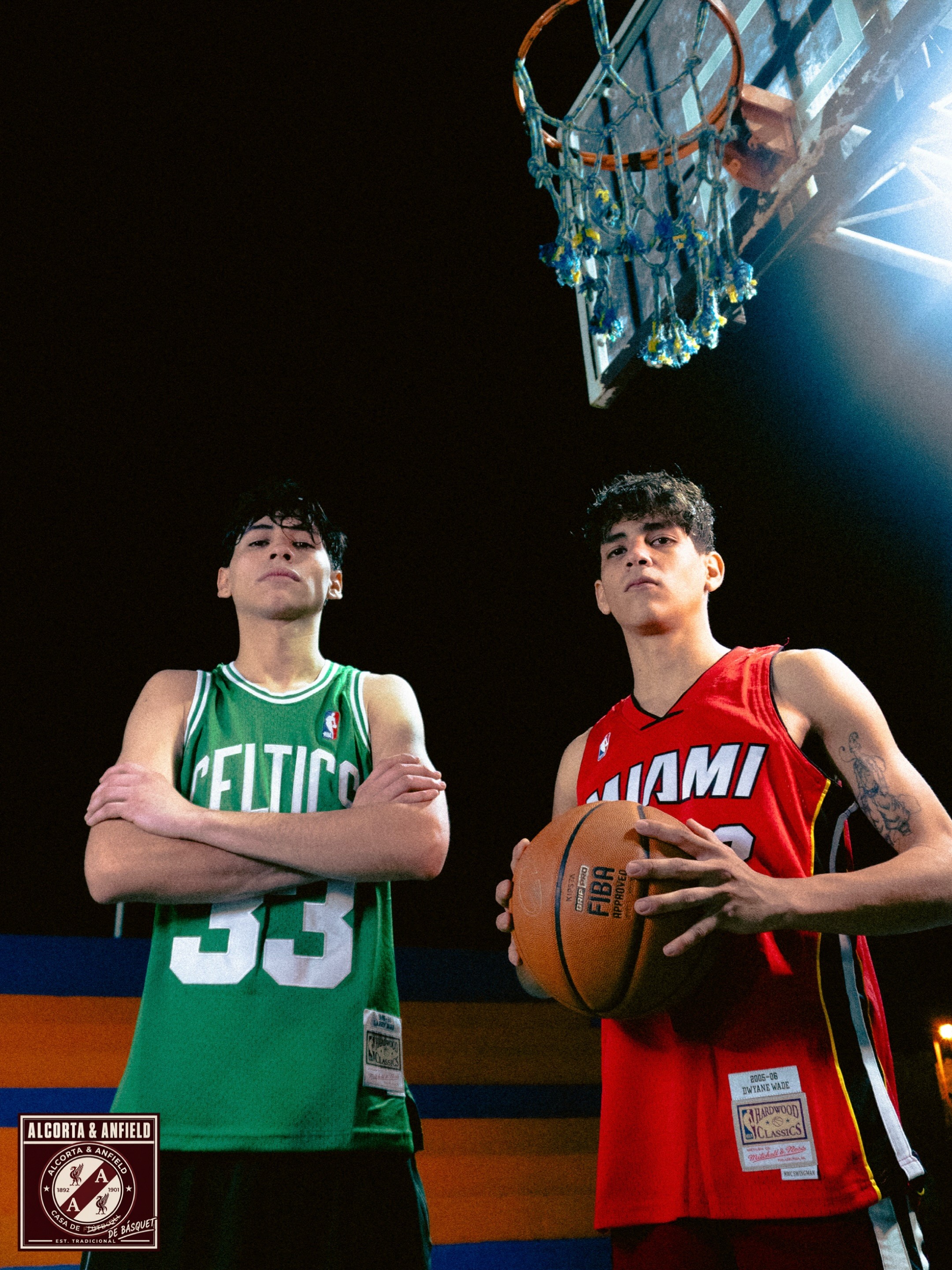 Dos chicos con camisetas de básquet de Celtics y Miami, bajo el aro de la cancha